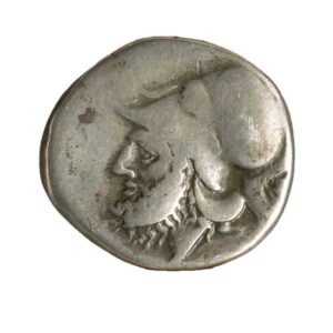 Didrachm coin minted between 280 B.C.E.-276 B.C.E.  An unevenly round coin with a profile of a man's face with a cap.